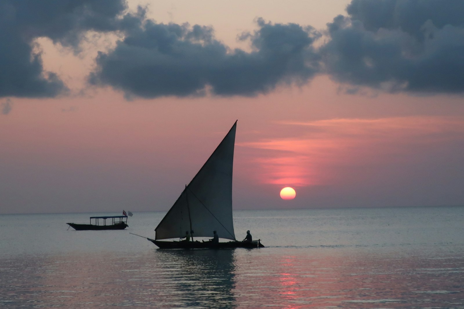 photograph of sail boat on calm body of water during golden hour